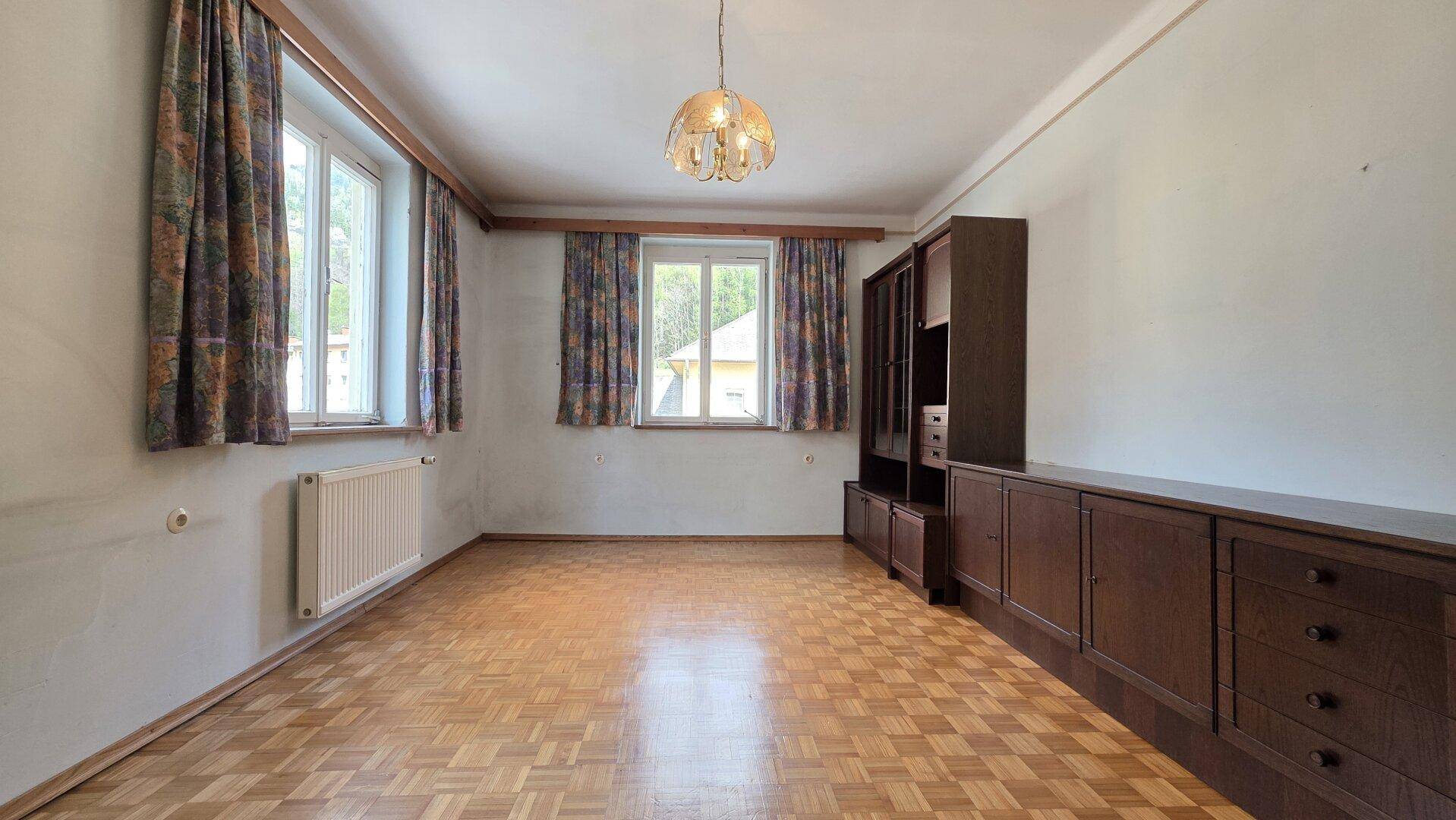Leerer Raum mit Parkettboden, Holzschränken und Fenstern, bereit zur individuellen Gestaltung.