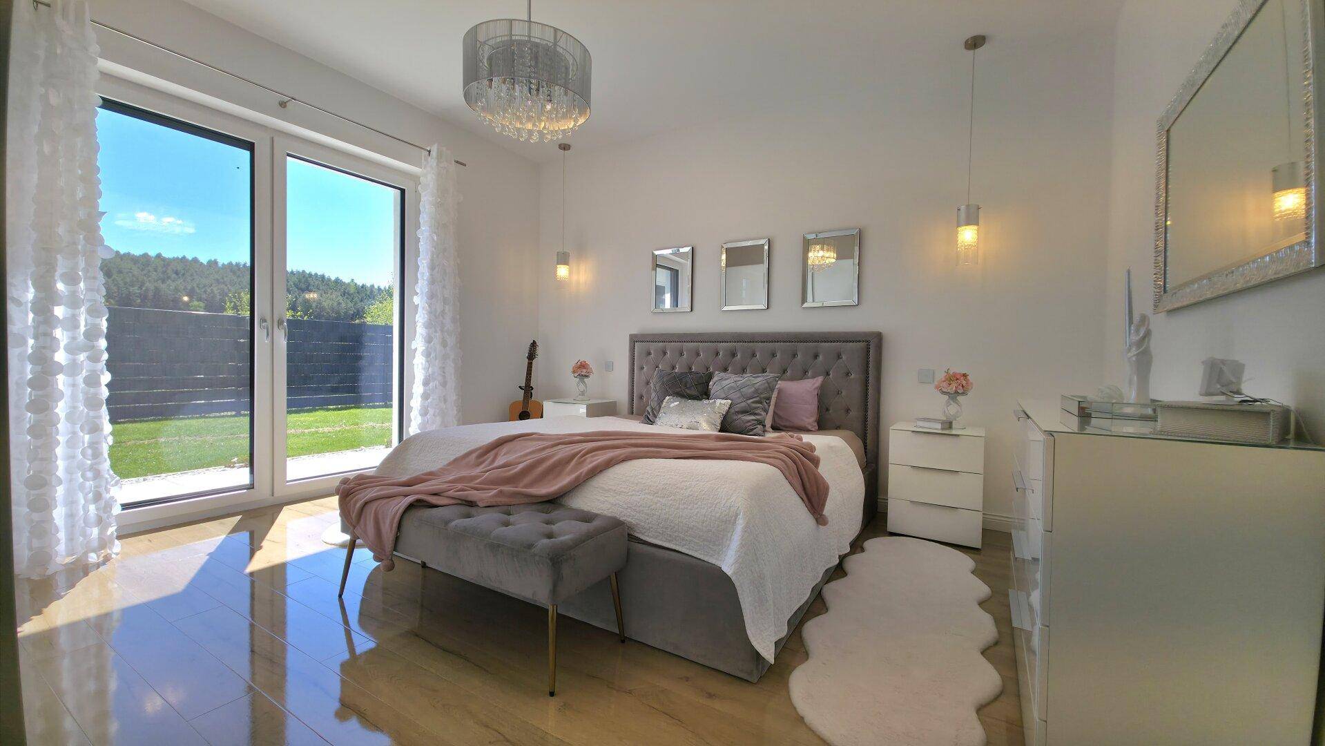 Helles Schlafzimmer mit Zugang zum Garten, modernem Bett und stilvoller Beleuchtung, einladend und komfortabel.