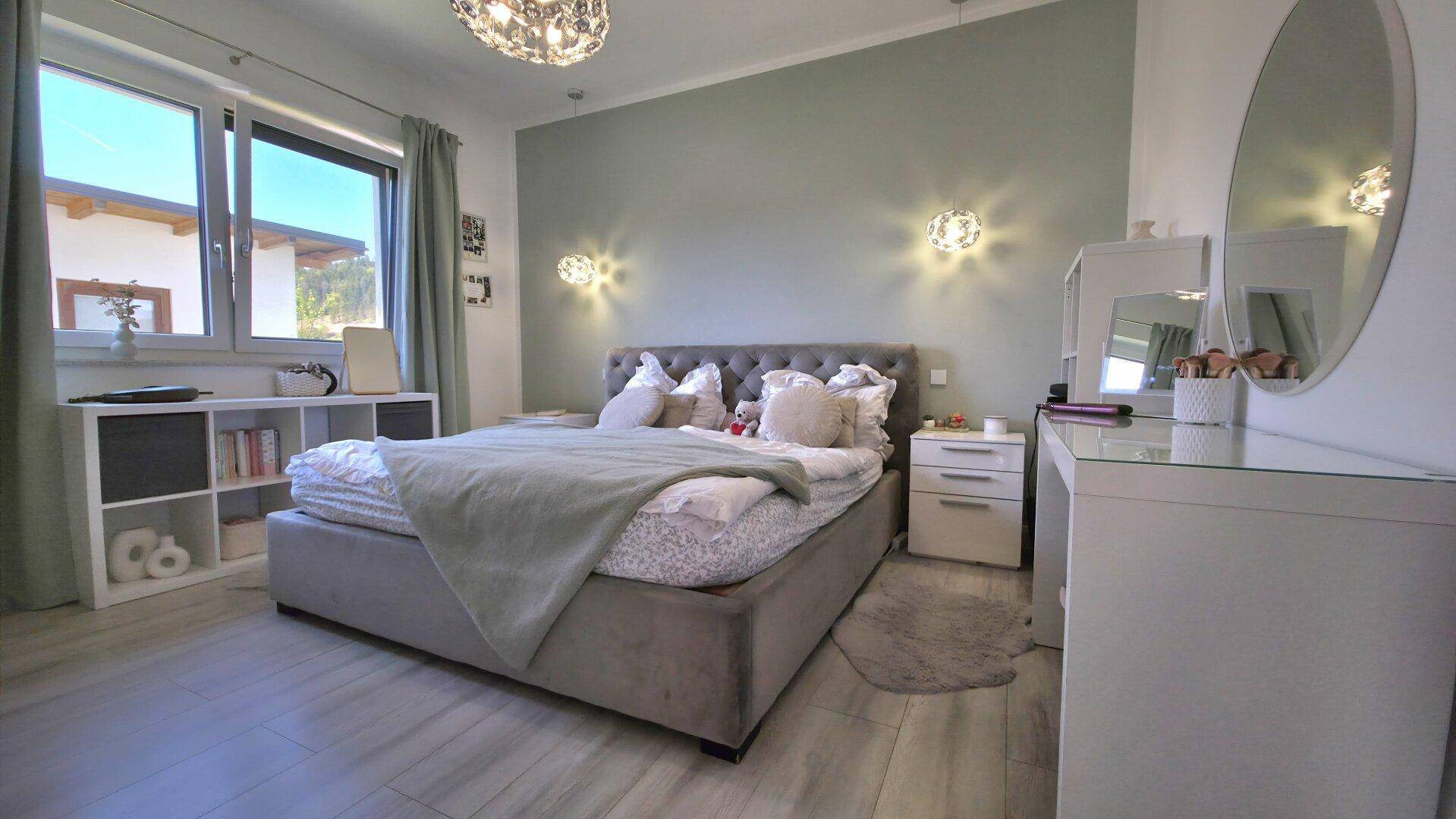 Gemütliches Schlafzimmer mit hellem Holzboden, modernem Bett und dezenter Wandfarbe, mit viel Tageslicht.