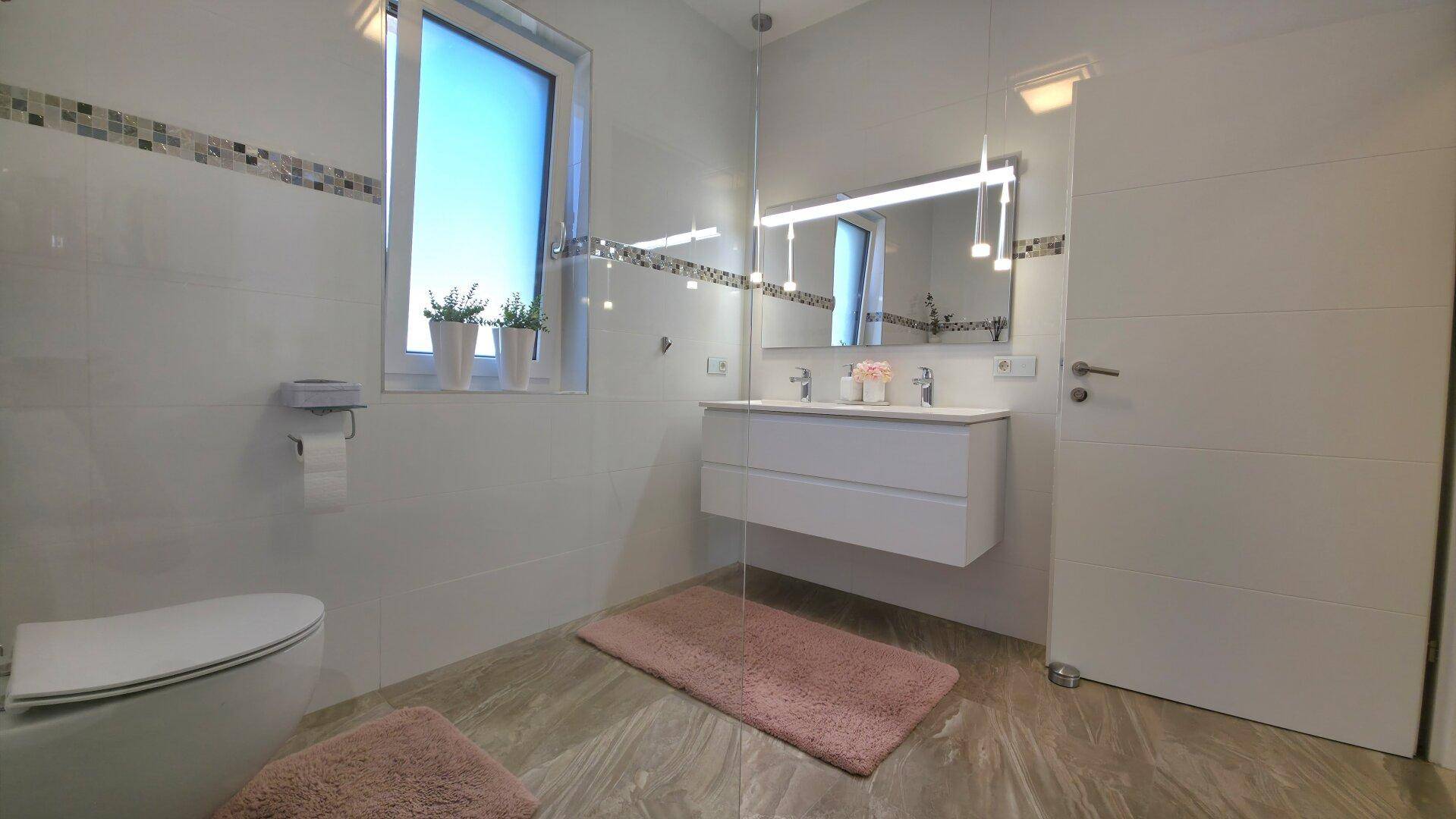 Helles Badezimmer mit Doppelwaschbecken, großem Spiegel und wandhängendem WC, modern und funktional gestaltet.