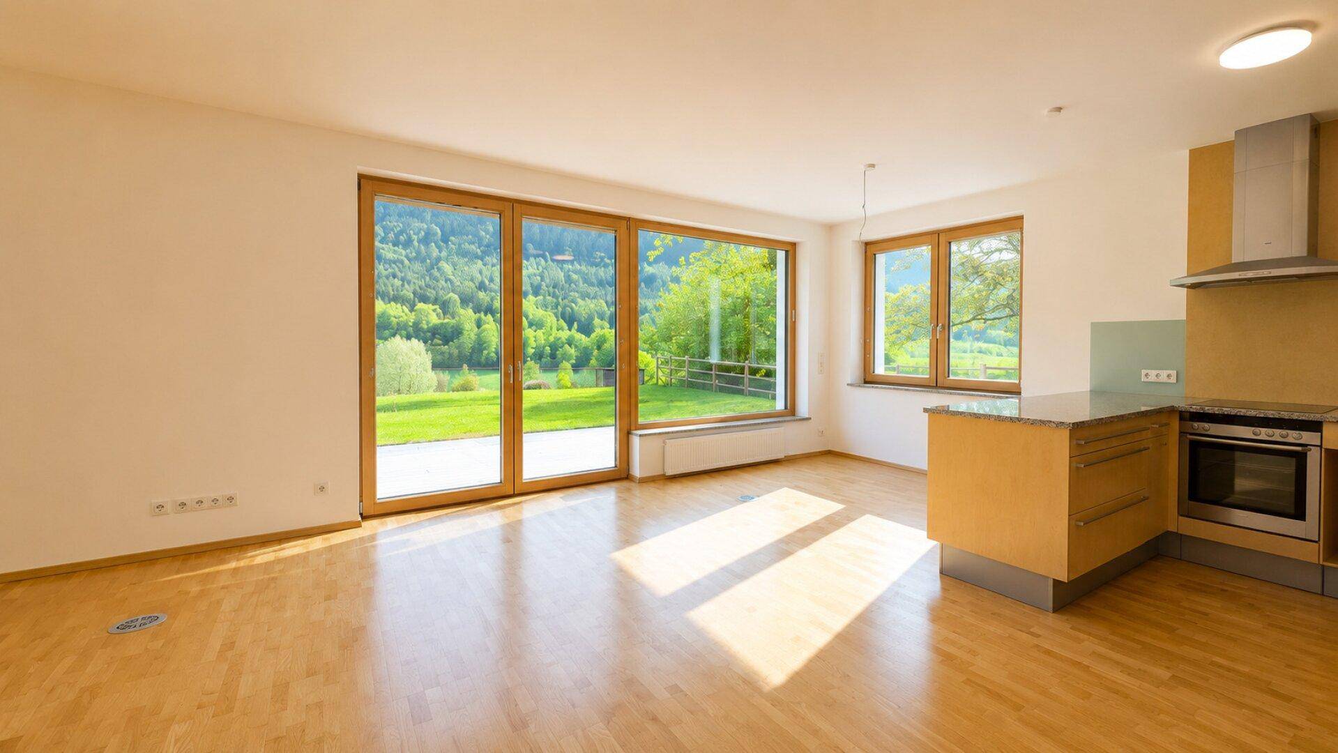 Lichtdurchfluteter Wohnbereich mit Holzfußboden, großen Fenstern und Blick ins Grüne.