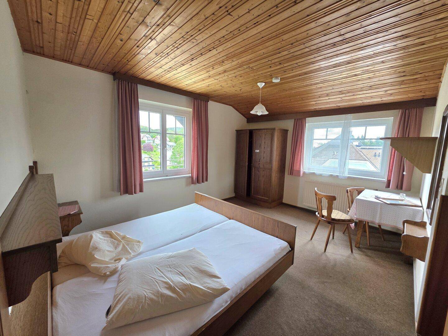 Gemütliches Schlafzimmer mit Holzdecke, Teppichboden und zwei Einzelbetten.