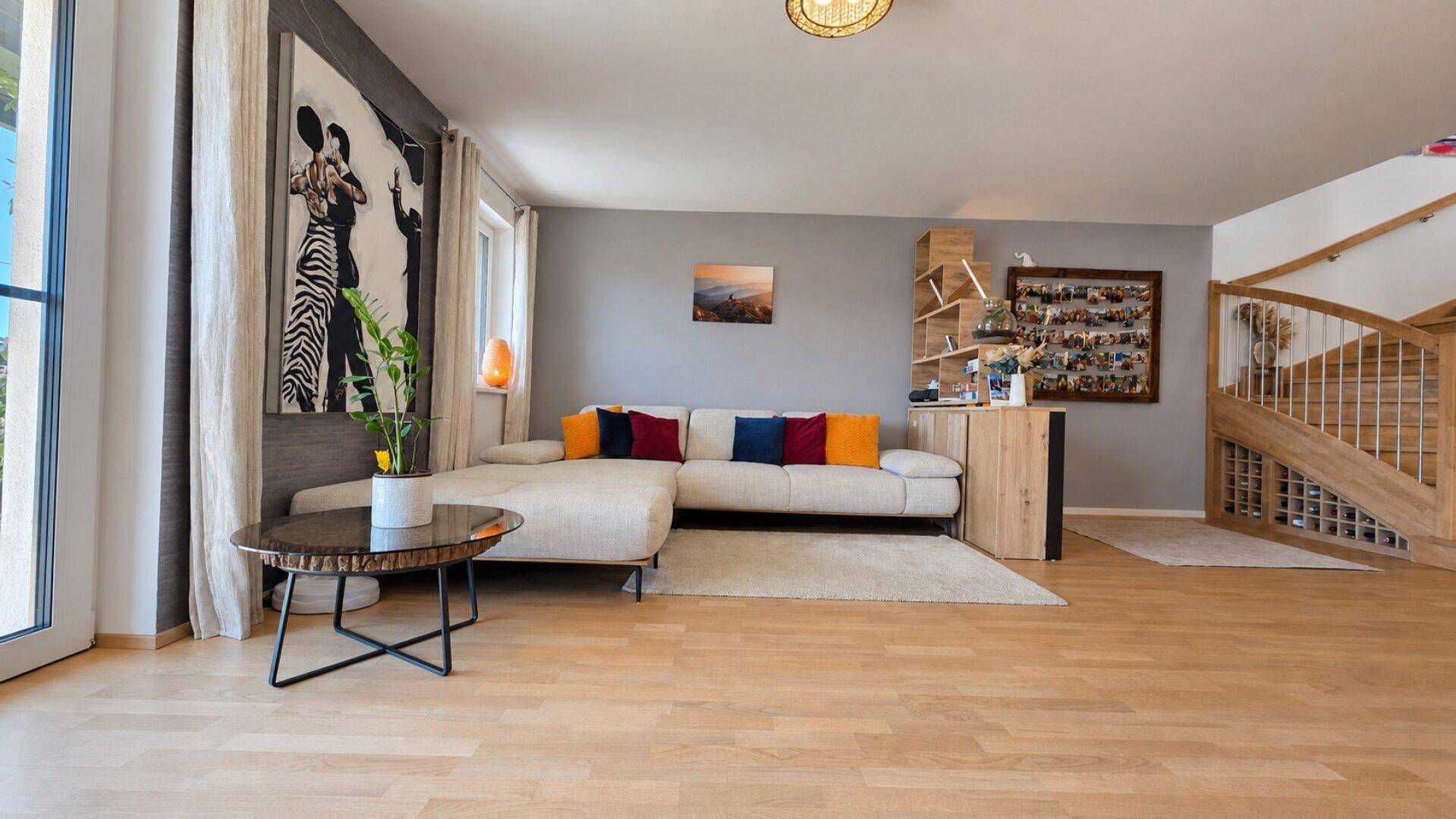 Helles Wohnzimmer mit großem Ecksofa, Holzboden und eleganter Holztreppe.