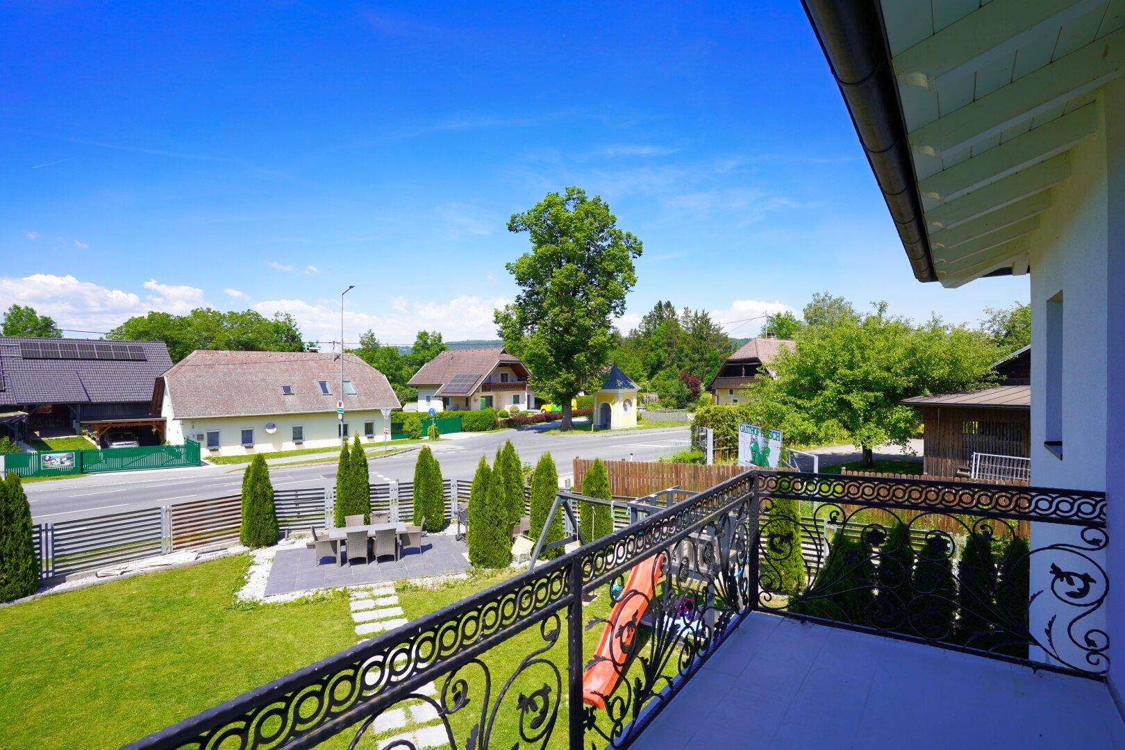 Blick vom Balkon auf den Garten, Spielplatz und die umliegende Landschaft.