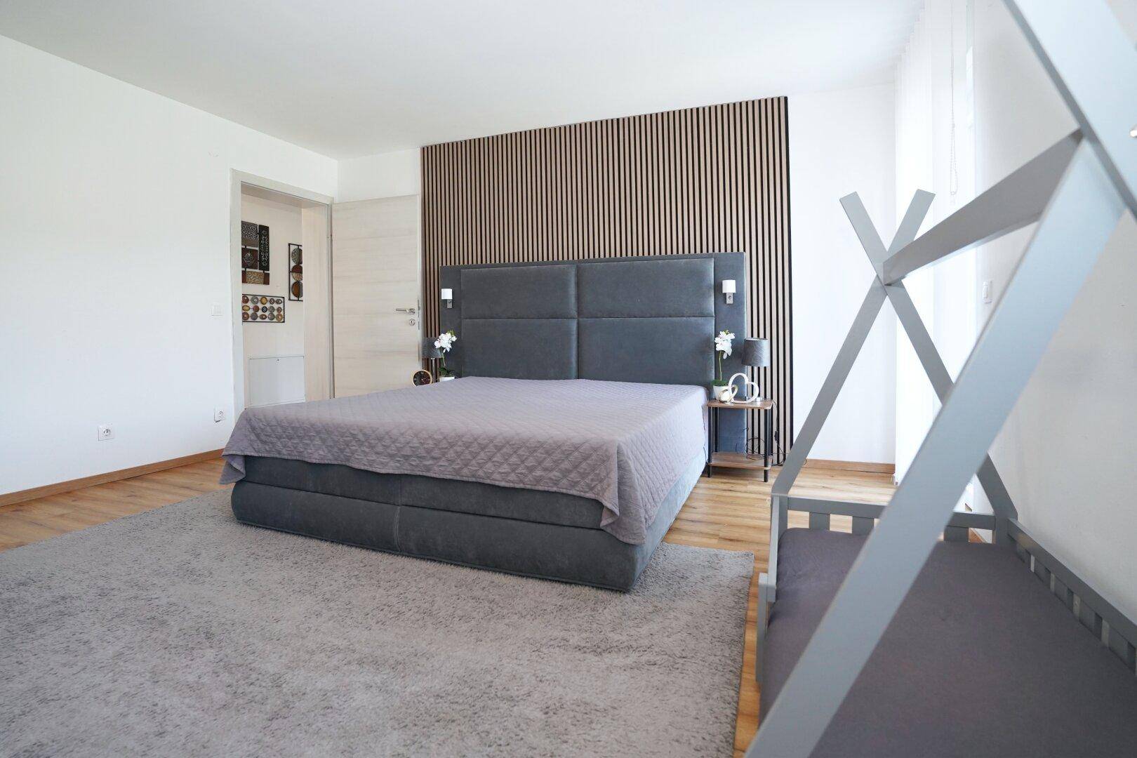 Geräumiges Schlafzimmer mit großem Bett, Holzwandverkleidung und hellem Teppich.