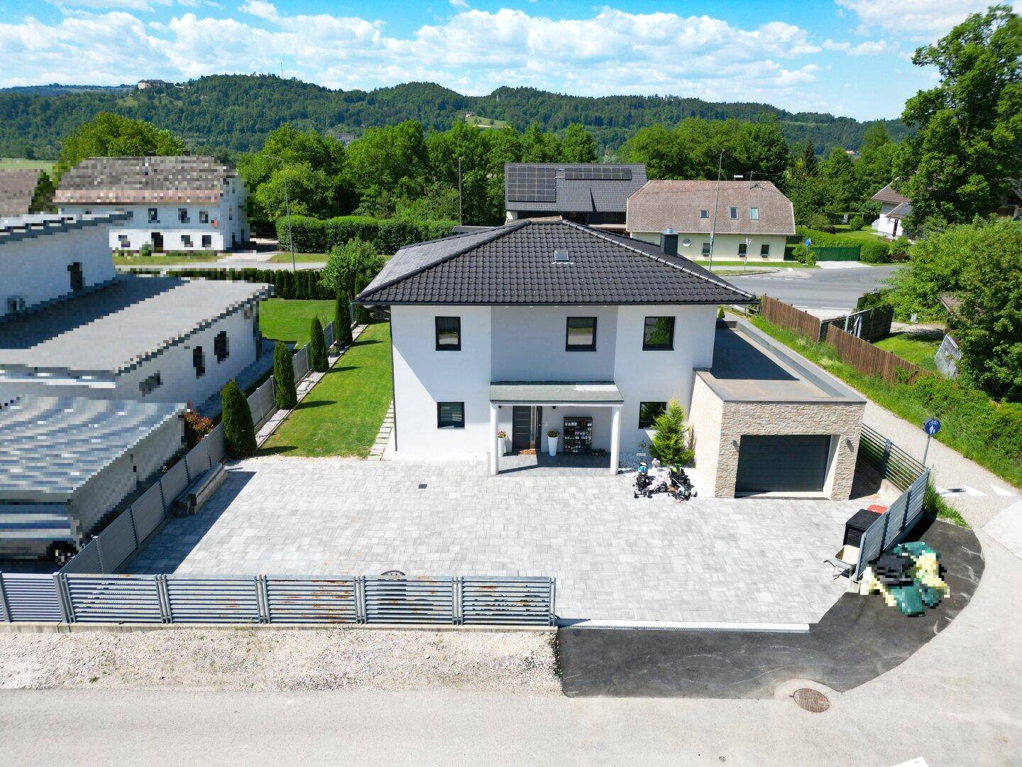 Luftaufnahme des Einfamilienhauses mit gepflasterter Zufahrt und angrenzender Garage.
