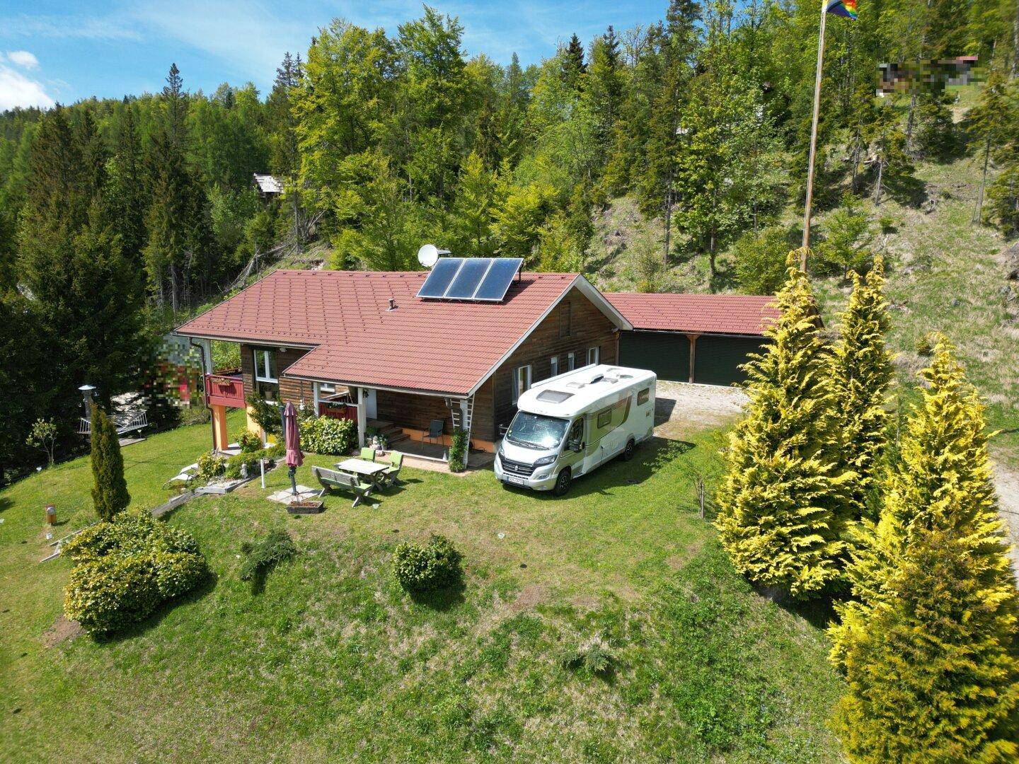 Gesamtansicht des Hauses mit angrenzendem Garagengebäude und Wohnmobil auf dem Grundstück.