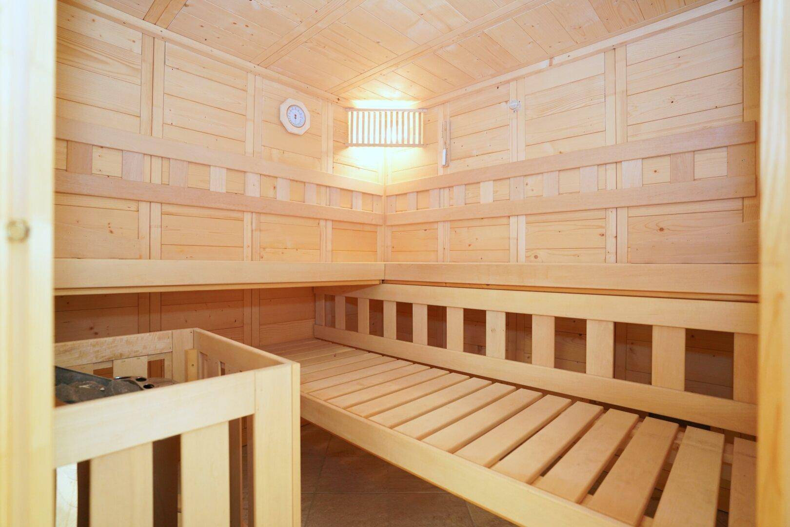 Innenansicht einer Holzsauna mit Bänken und Heizofen.
