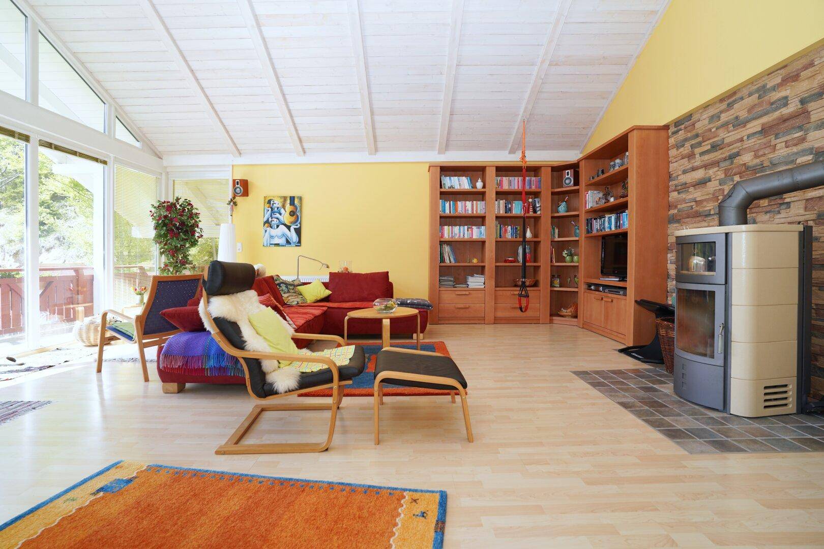 Geräumiges Wohnzimmer mit Kaminofen, Bücherregalen und hellem Laminatboden.