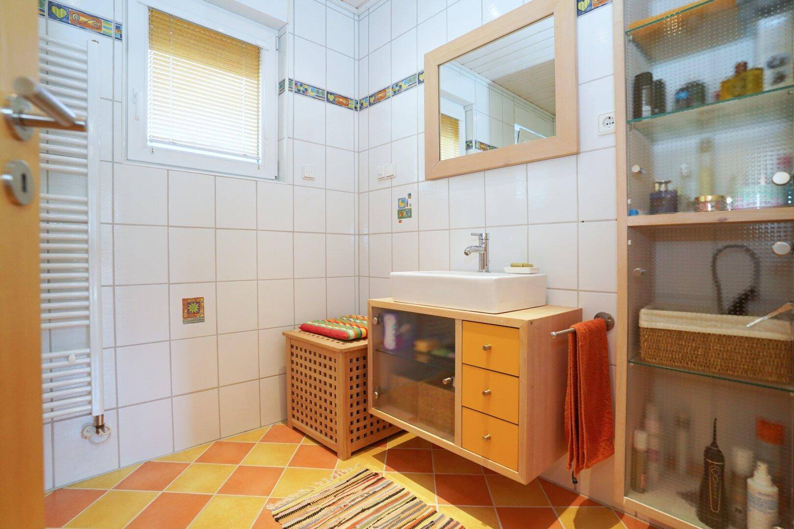 Badezimmer mit Waschbecken, Spiegelschrank und farbigen Fliesen.