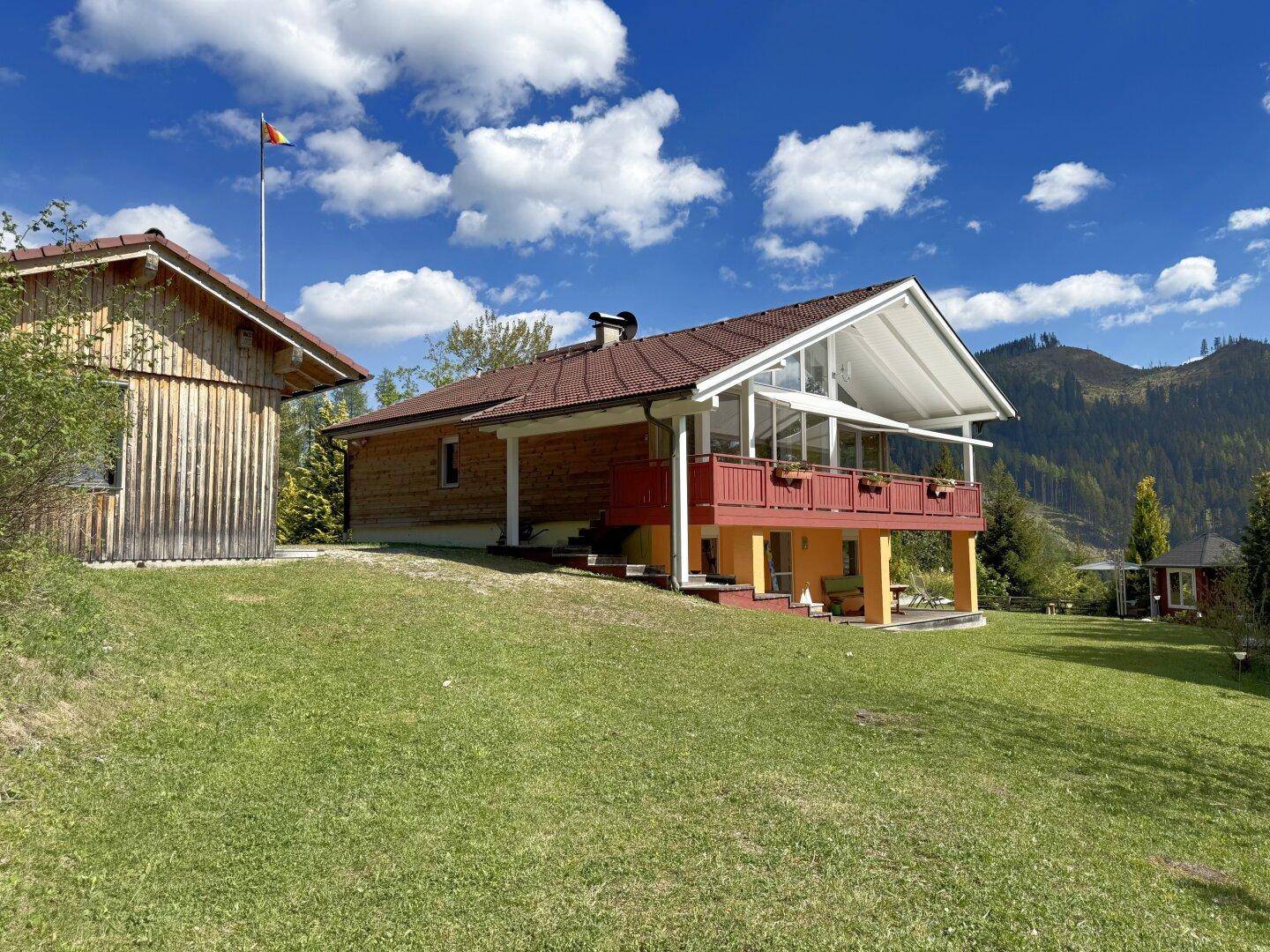 Charmantes Holzhaus mit großem Balkon und Blick auf die umliegende Berglandschaft.