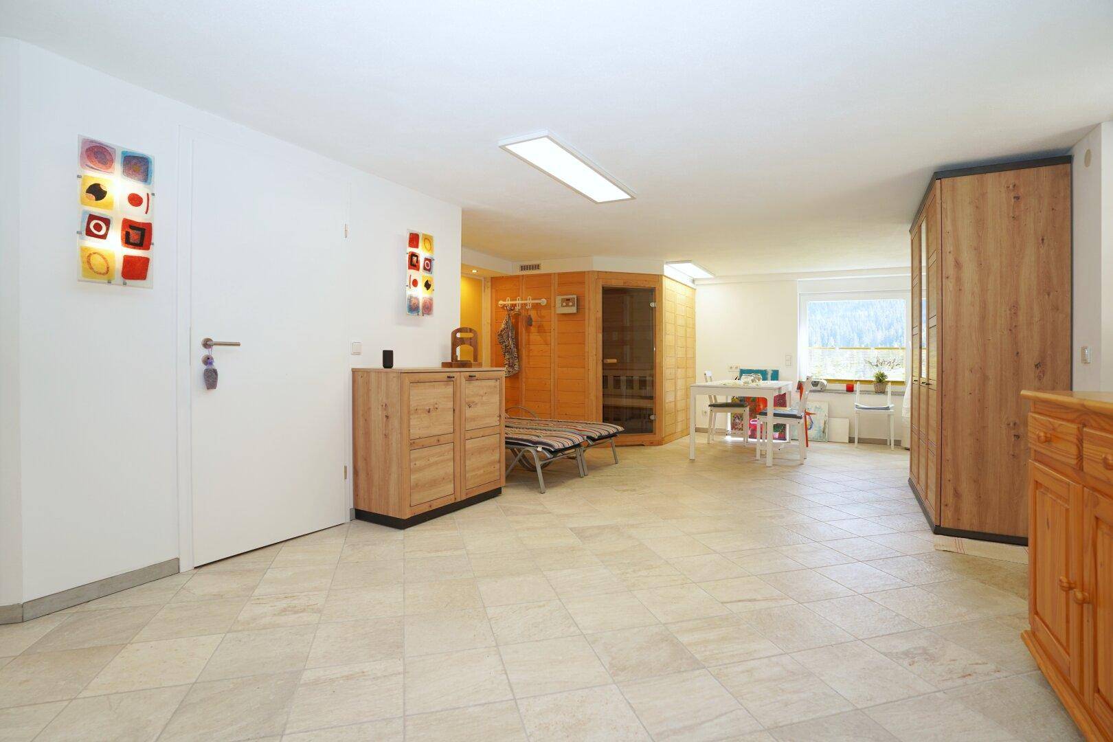 Geräumiger Wellnessbereich im Untergeschoss mit Sauna und Fliesenboden.