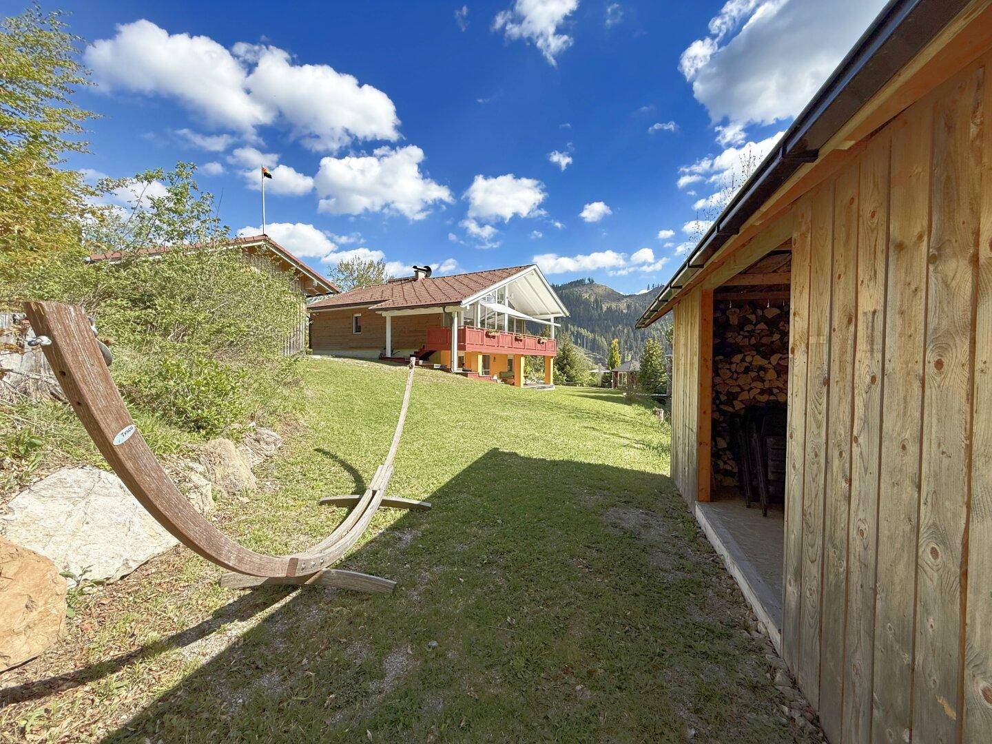 Großer Gartenbereich mit Hängematte und Blick auf das Haupthaus und die Berge.