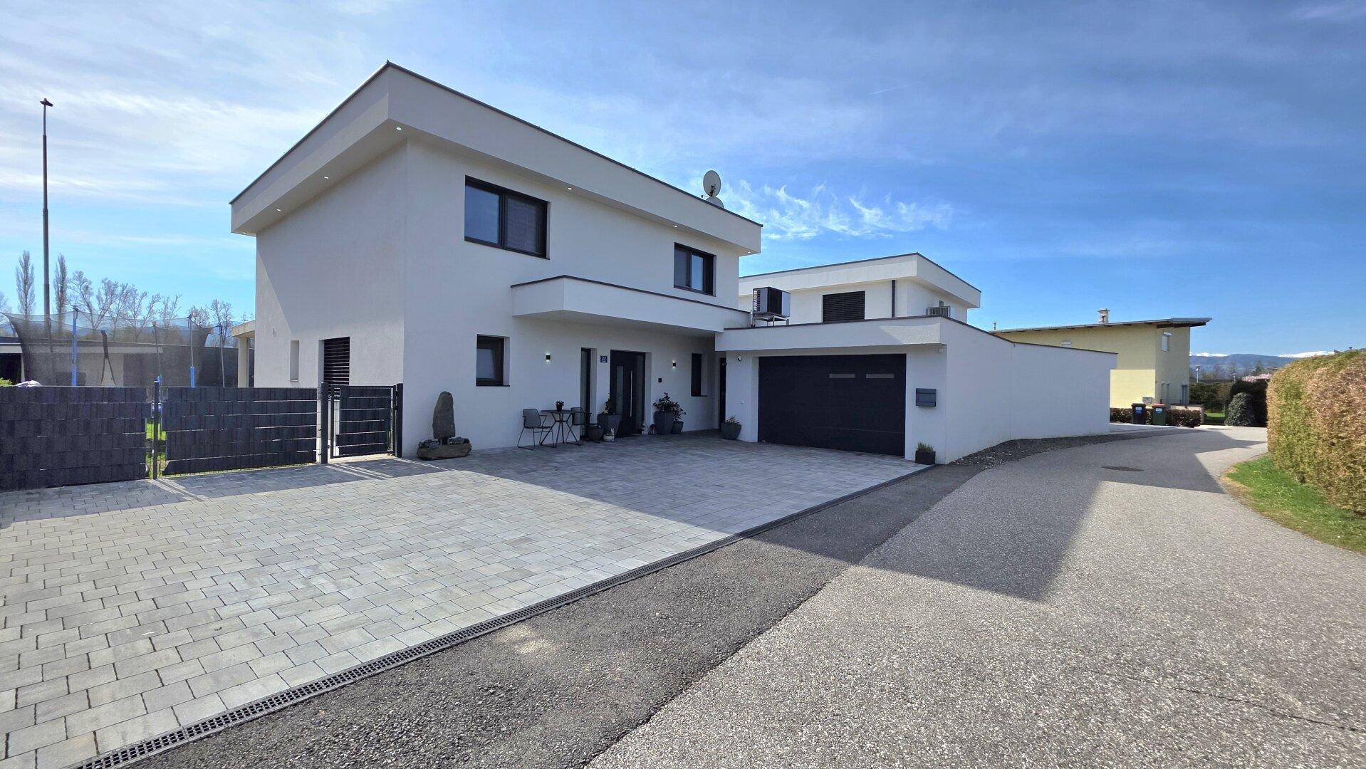 Modernes Einfamilienhaus mit Doppelgarage, gepflasterter Auffahrt und Vorgarten.