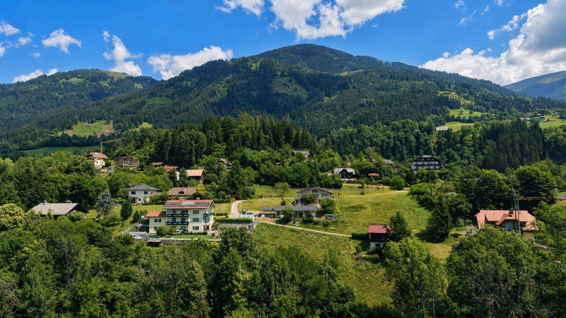 Siedlung am Hang eines bewaldeten Berges unter einem strahlend blauen Himmel.