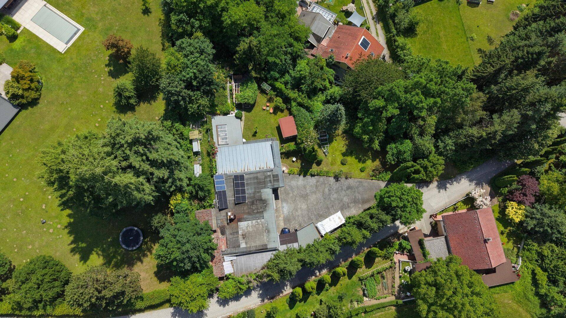 Luftaufnahme des Anwesens mit Haus, üppiger Vegetation und einem Pool in der Ferne.