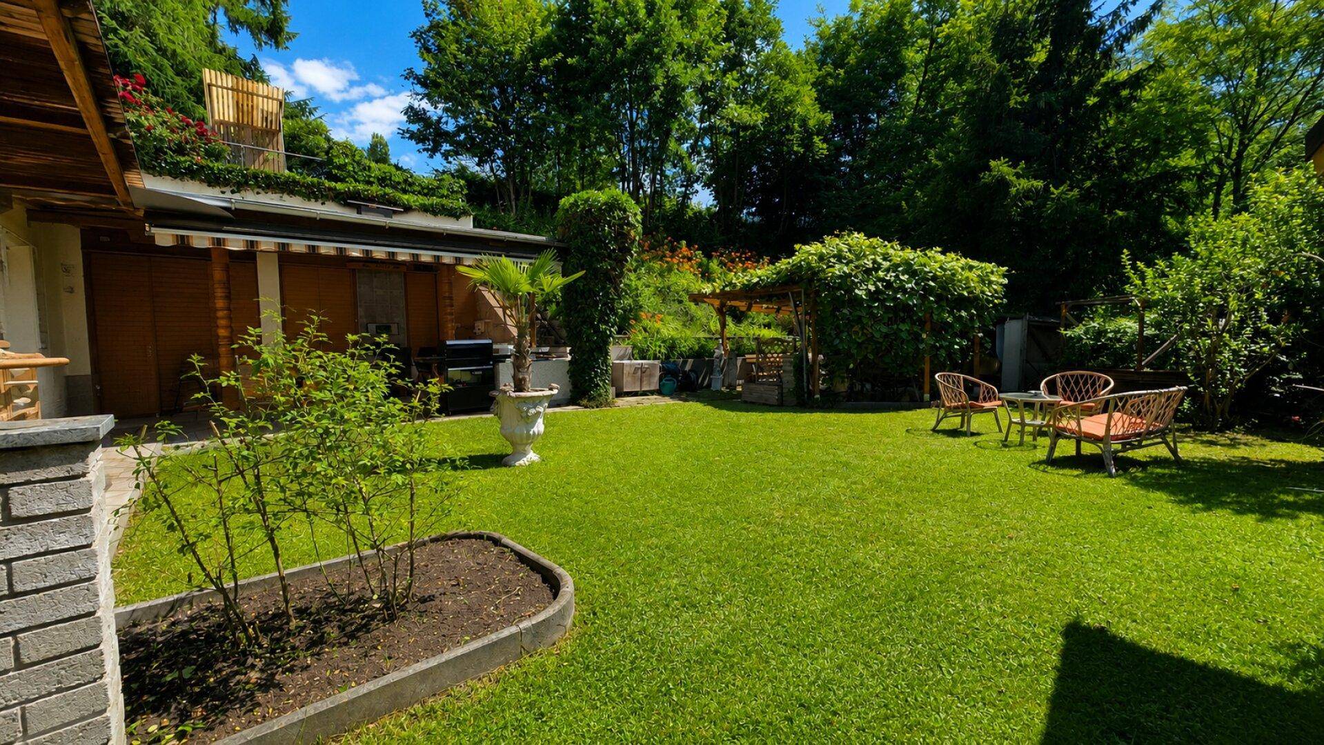 Weitläufiger Garten mit Rasen, Sitzgelegenheiten und üppiger Bepflanzung.