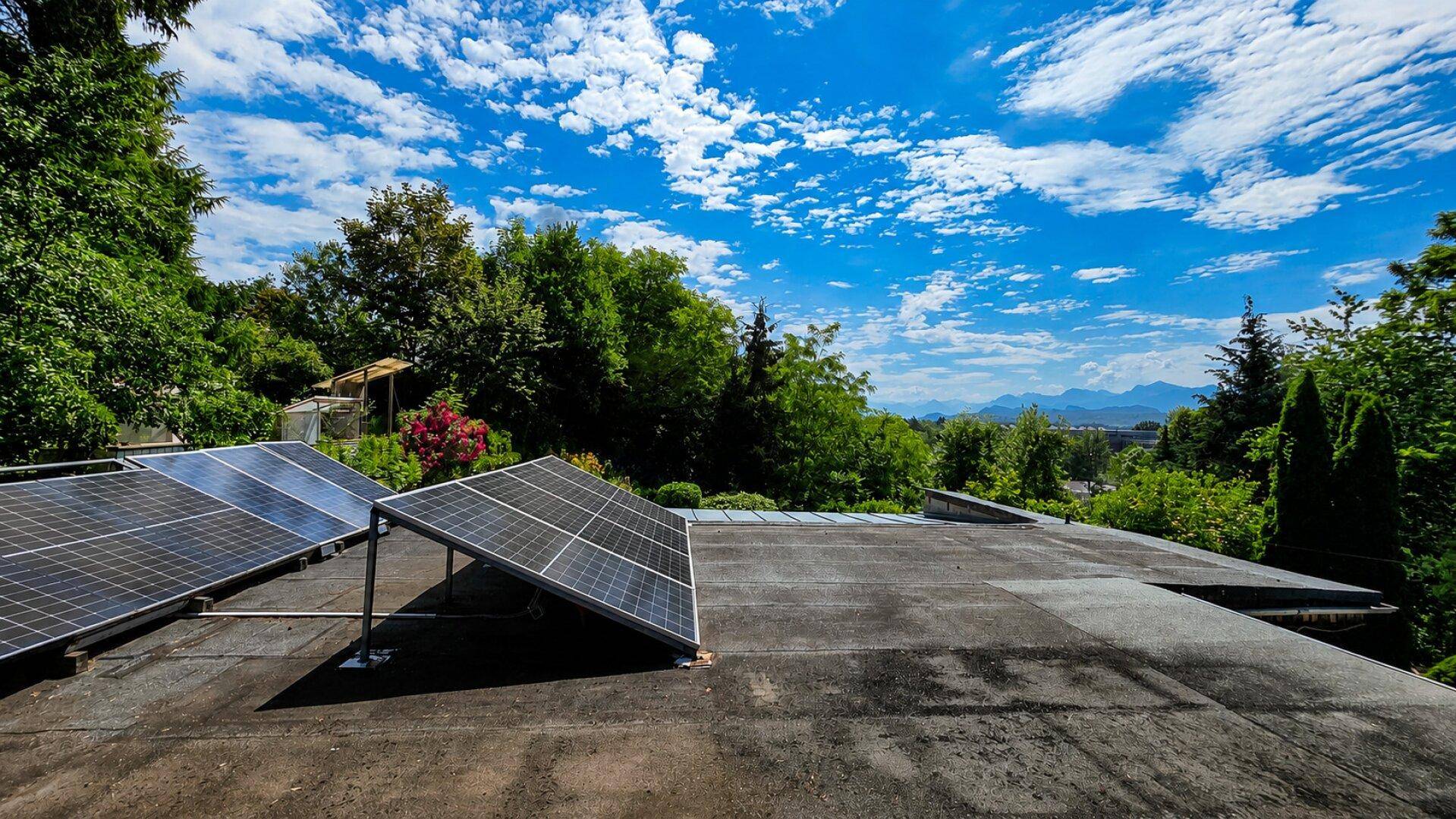 Flachdach mit installierten Solarmodulen und weitem Blick auf die Berge.