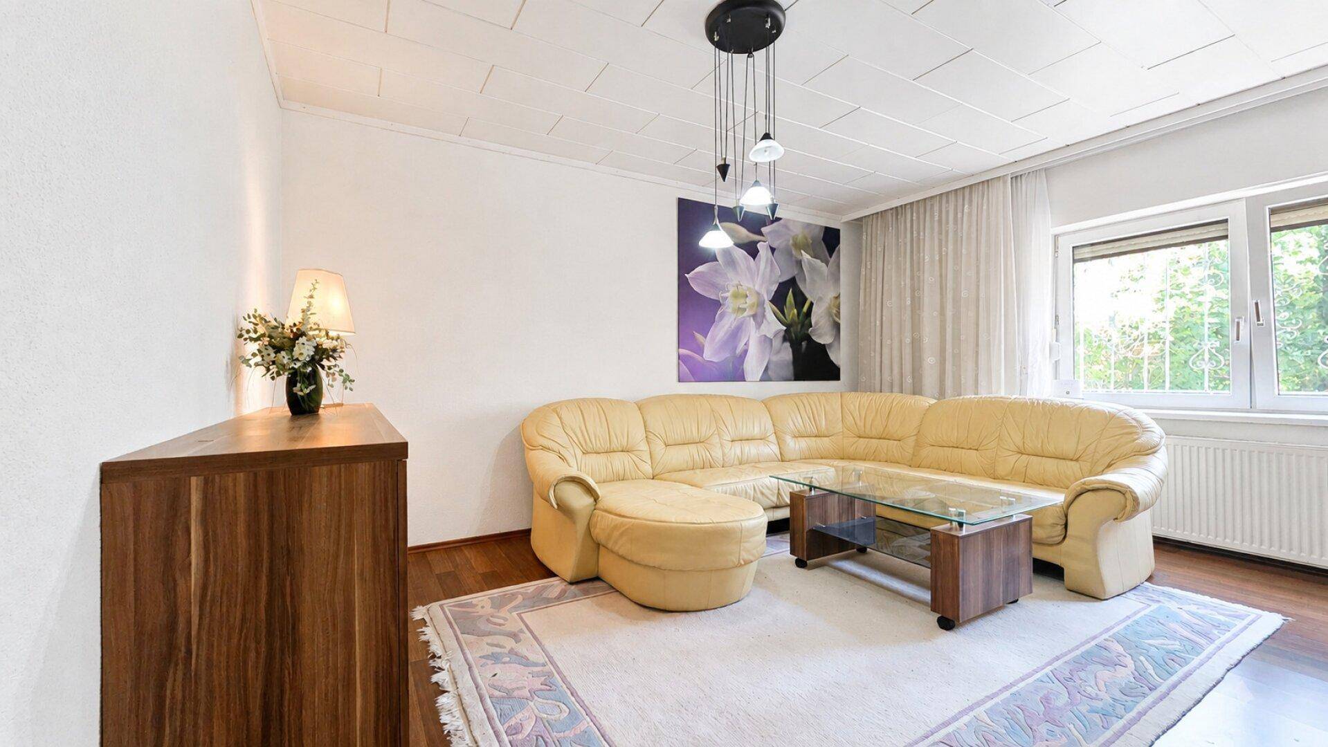 Gemütliches Wohnzimmer mit großem Ecksofa, Couchtisch und Teppichboden.