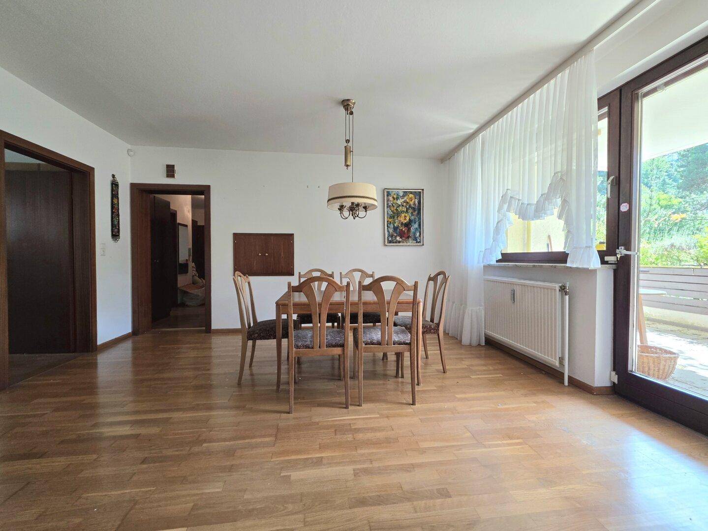 Heller Essbereich mit Holztisch und Stühlen, Parkettboden und Zugang zum Balkon.
