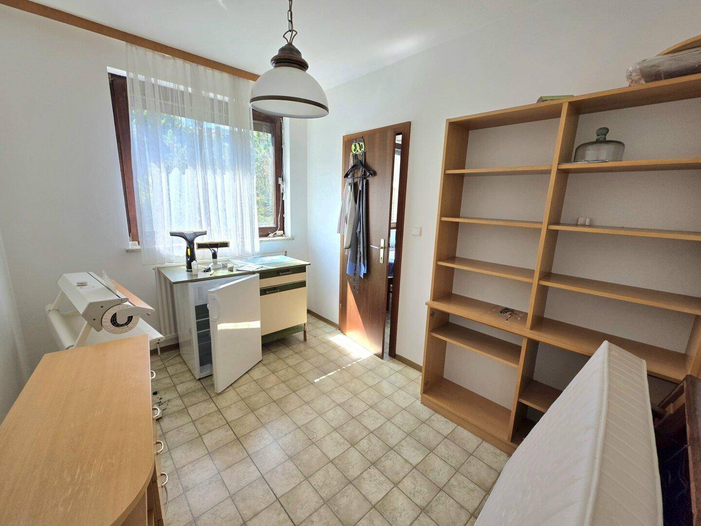 Praktischer Abstellraum mit Fliesenboden, Regal und kleinem Kühlschrank.