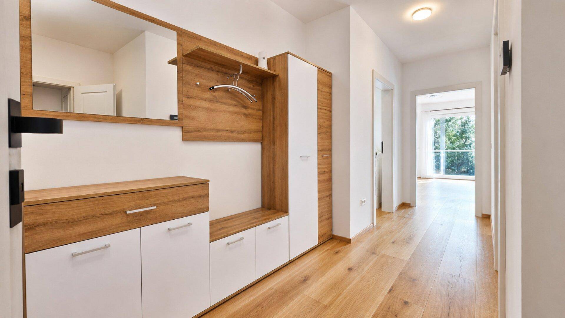 Heller Flur mit Holzboden und moderner Garderobe mit Spiegel und Stauraum.