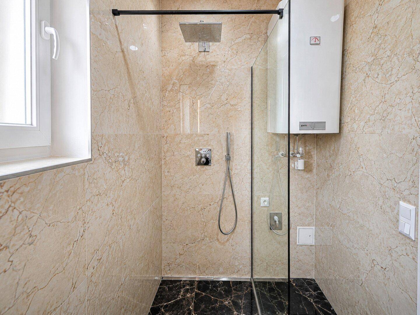 Geräumige ebenerdige Dusche mit beigefarbenen Marmorfliesen und Regenduschkopf in einem modernen Bad.
