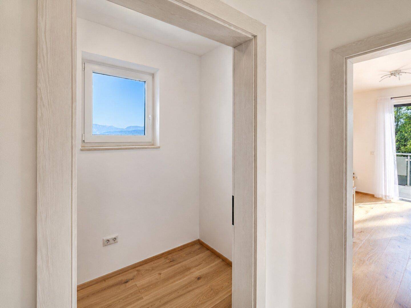 Kleiner Raum mit Fenster und Holzboden, ideal als Abstellraum oder begehbarer Kleiderschrank.
