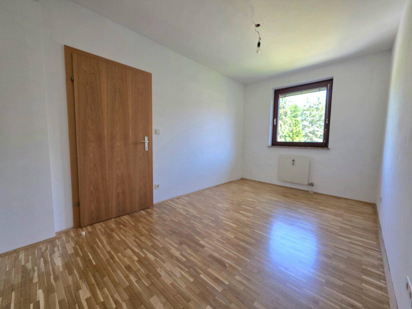Geräumiges Schlafzimmer mit Parkettboden und Holztür, bietet eine ruhige Atmosphäre.