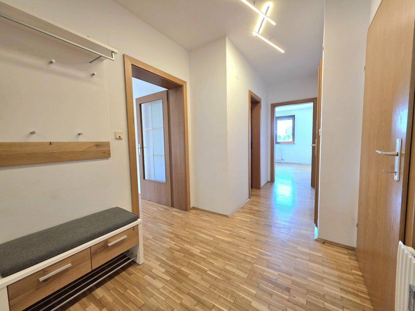 Heller Flur mit Parkettboden und Garderobe, verbindet die verschiedenen Wohnbereiche.