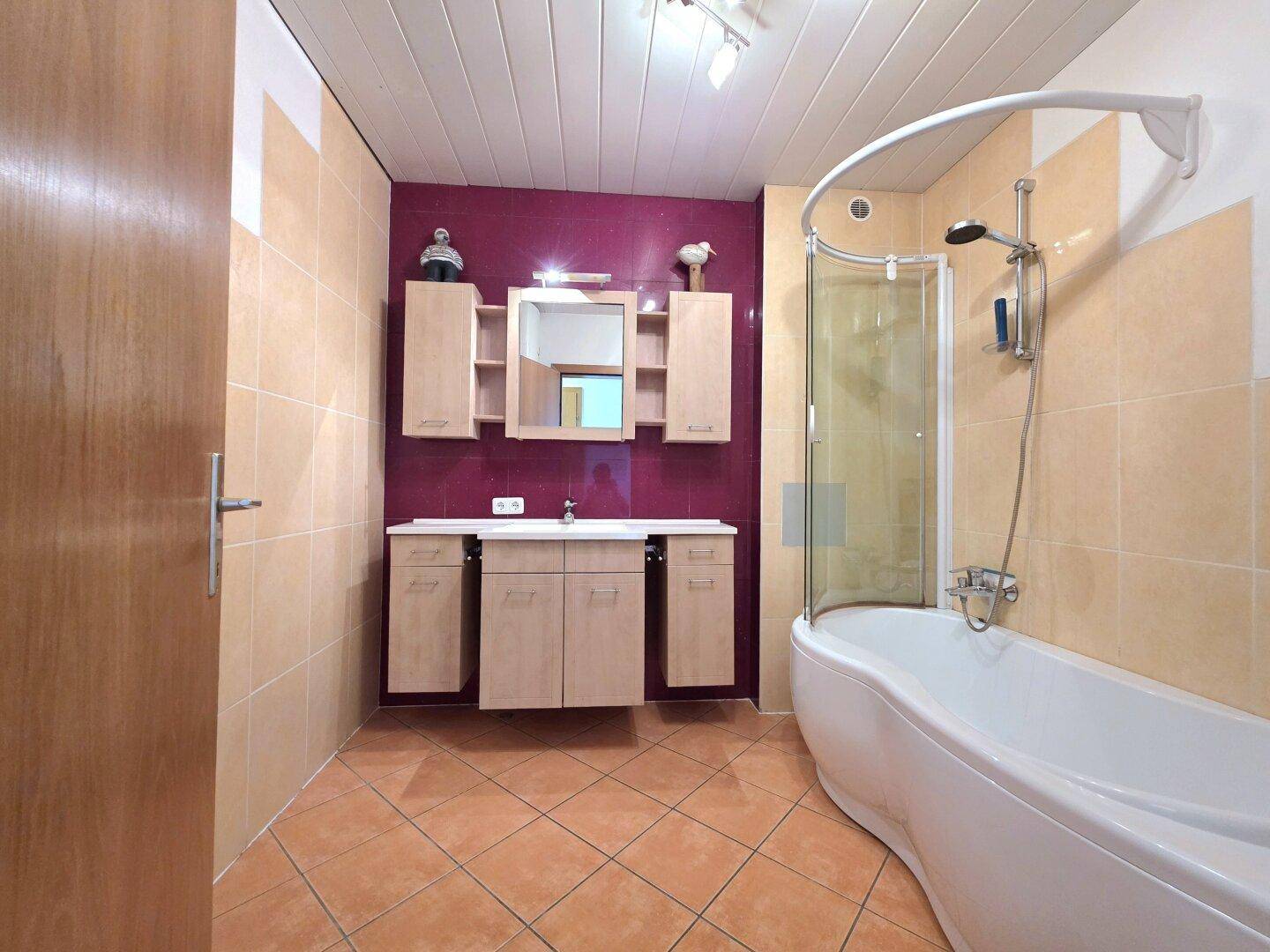 Badezimmer mit Badewanne, Dusche und farbigen Fliesen, bietet eine funktionale Ausstattung.