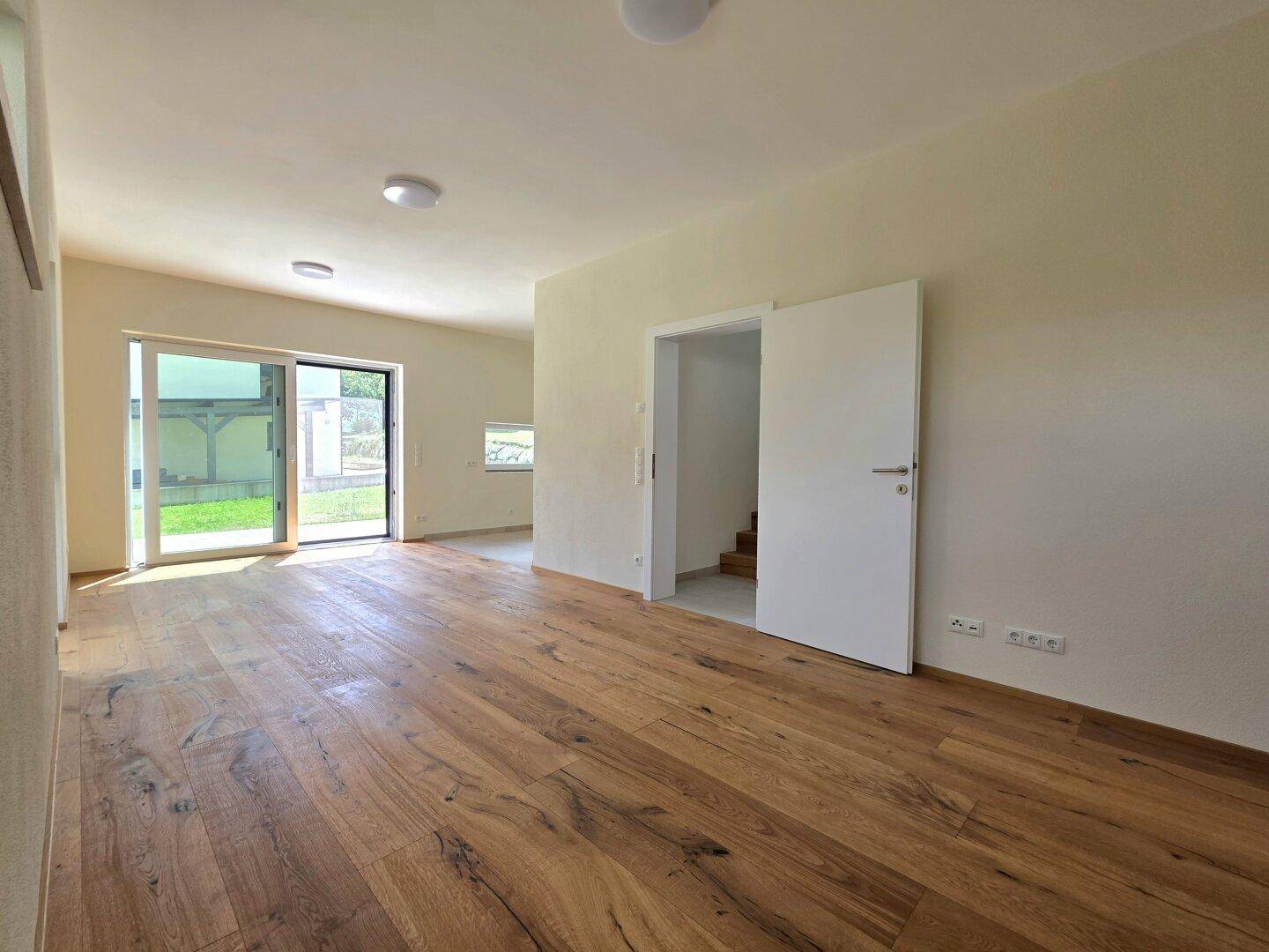 Geräumiger Wohnbereich mit Eichenparkett und Zugang zu weiteren Räumen und Treppe.