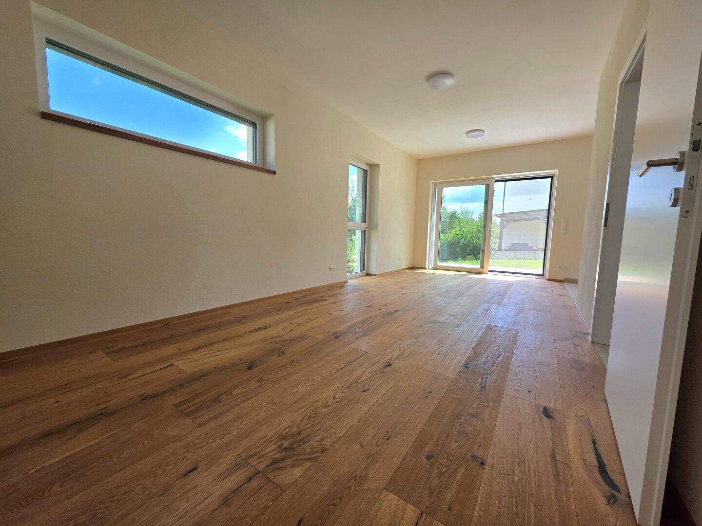 Heller Wohnraum mit hochwertigem Holzboden und großen Fenstern zum Garten.