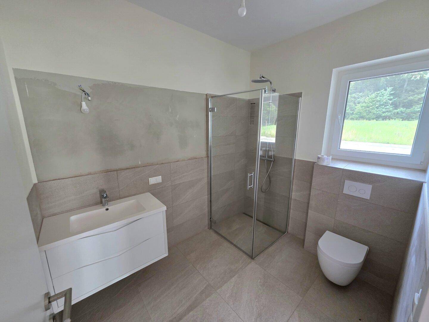 Modernes Badezimmer mit ebenerdiger Dusche, Waschtisch und Fenster.