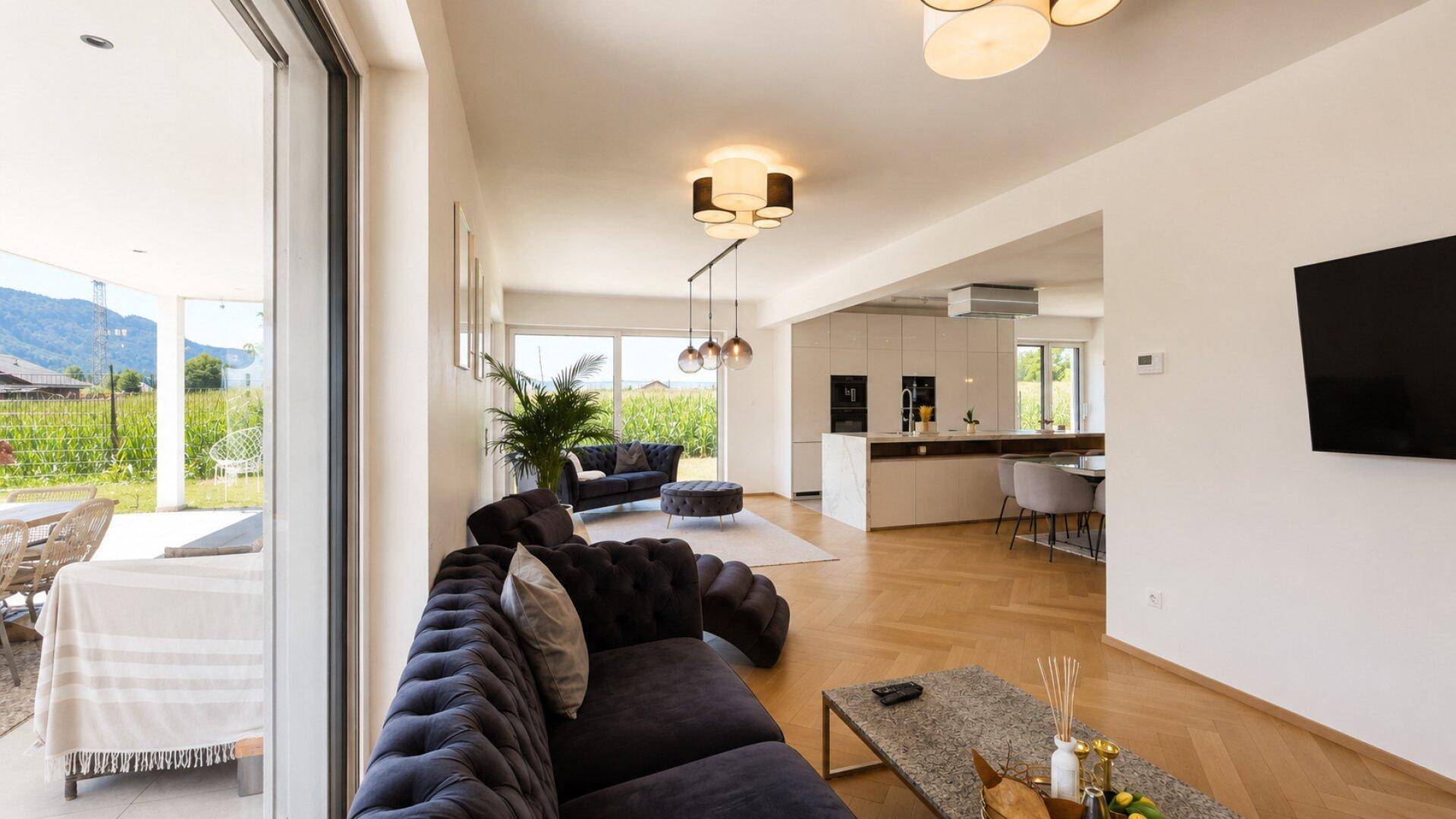 Helles Wohnzimmer mit großen Fensterfronten und Blick auf den Außenbereich mit Pool.