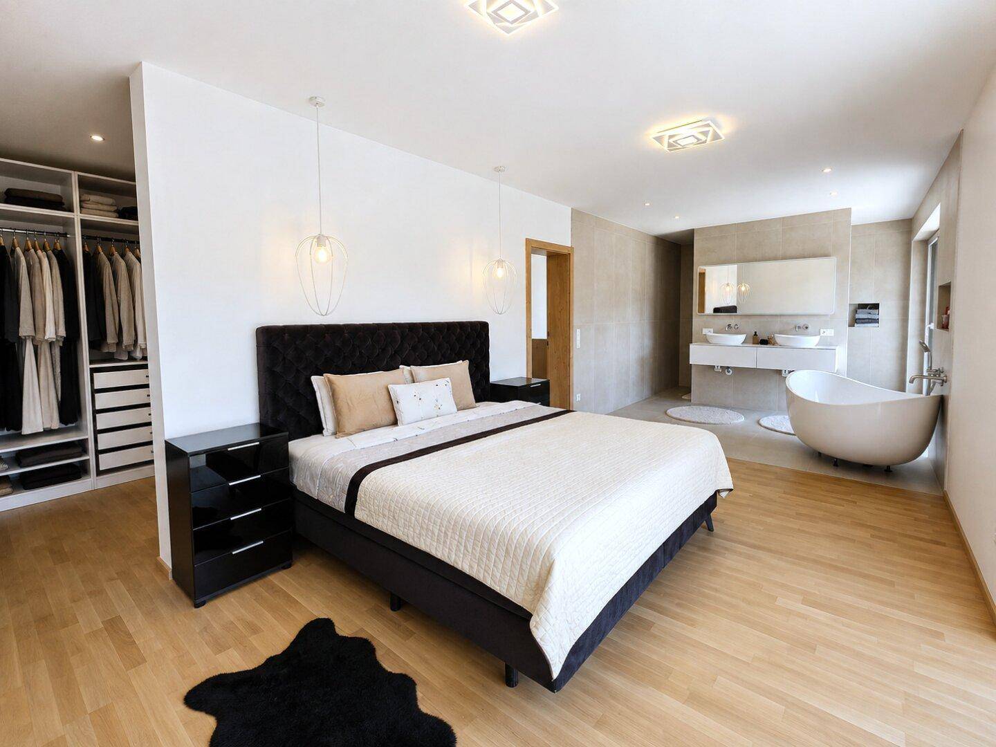 Elegantes Schlafzimmer mit offenem Badbereich, Doppelwaschbecken und begehbarem Kleiderschrank.