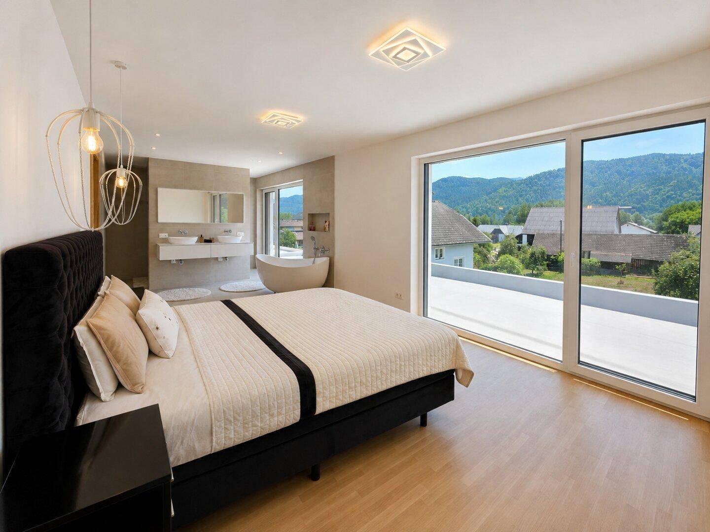 Geräumiges Schlafzimmer mit integriertem Bad, großen Fenstern und Bergblick.