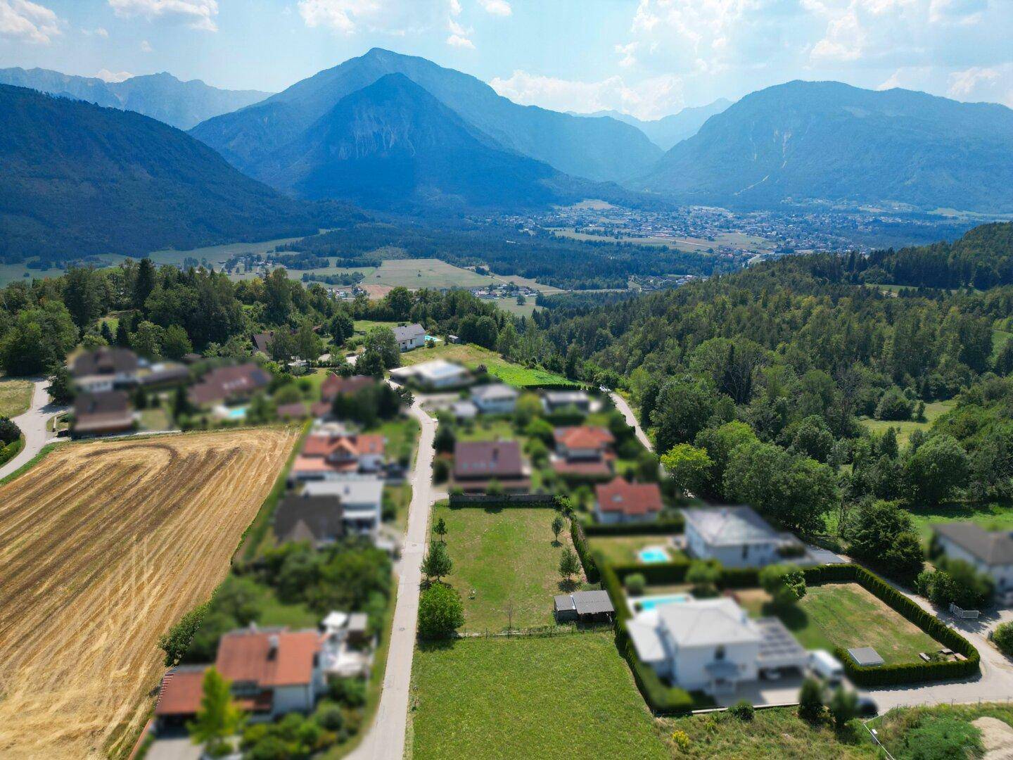 Panoramablick aus der Luft auf eine Wohngegend mit Häusern und einem weiten Tal mit Bergsicht.