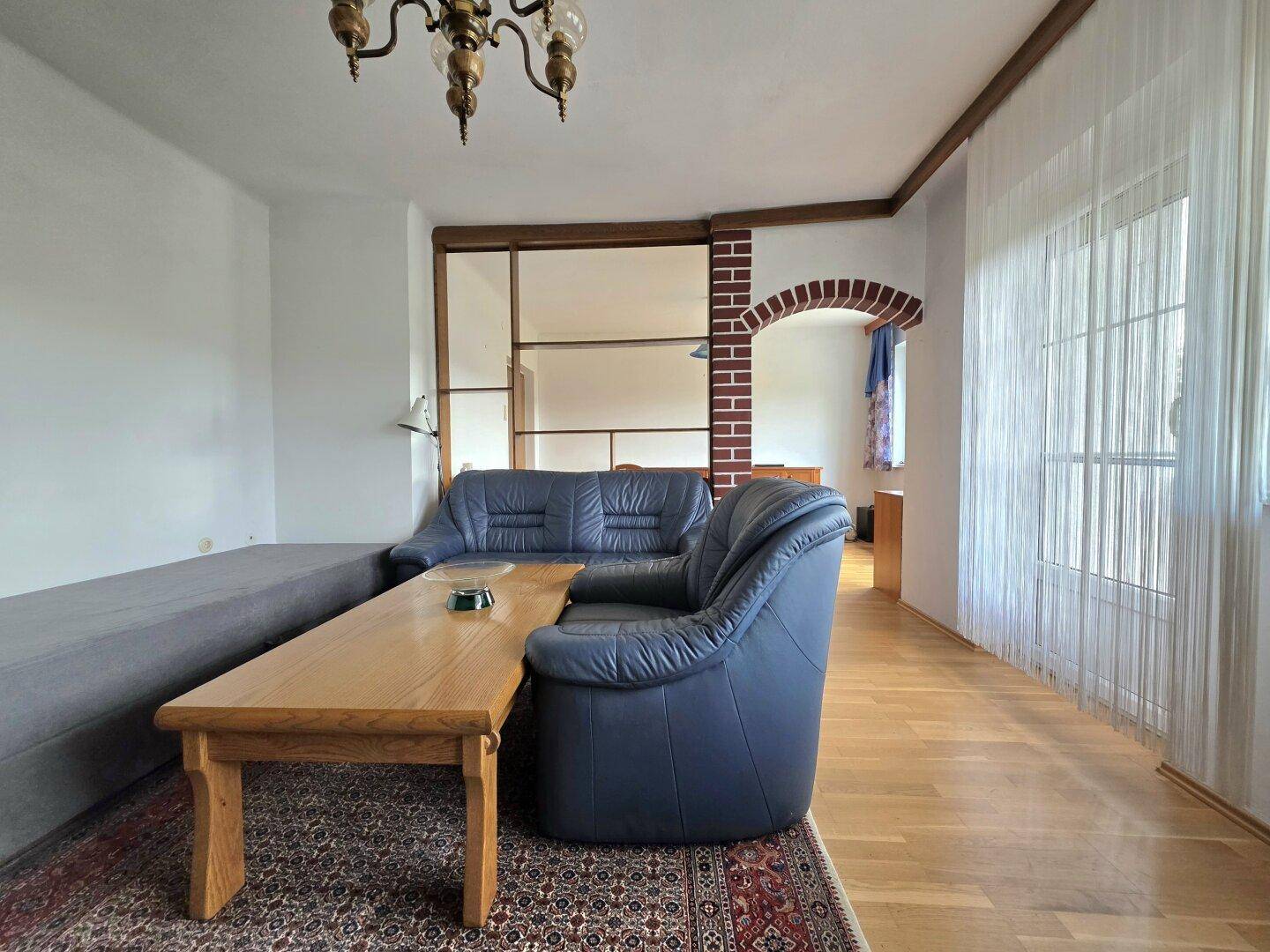 Gemütliches Wohnzimmer mit Ledersofa, Holztisch und Parkettboden in traditionellem Stil.