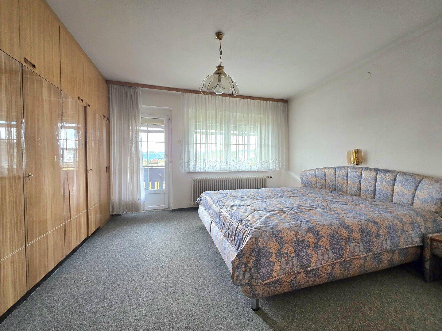 Schlafzimmer mit Doppelbett, Teppichboden und direktem Zugang zum Balkon mit Aussicht.