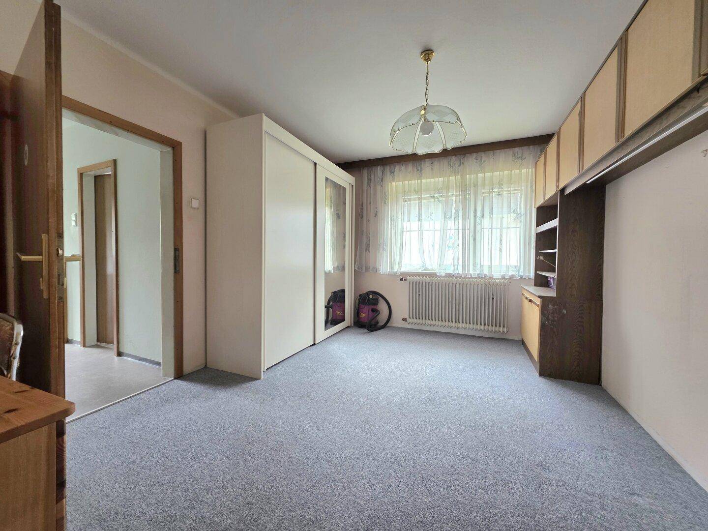 Helles Schlafzimmer mit Teppichboden, Schrank und Fenster für eine angenehme Atmosphäre.