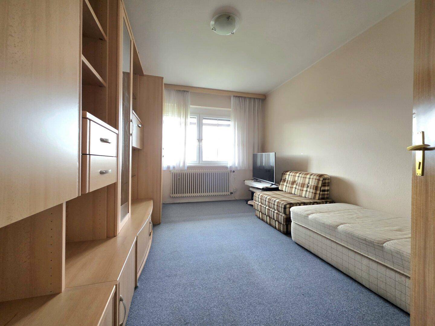 Zimmer mit Teppichboden, Einzelbett und Schrankwand, ideal als Gäste- oder Kinderzimmer.