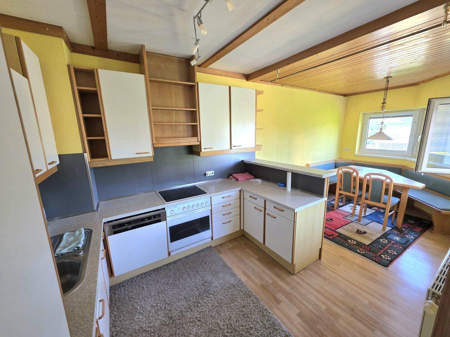 Traditionelle Wohnküche mit Holzbalken, Einbauküche und integriertem Essbereich mit Eckbank.