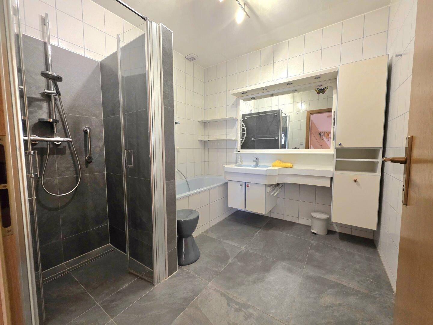 Modernes Badezimmer mit Dusche, Badewanne, Fliesenboden und einem einzelnen Waschbecken.