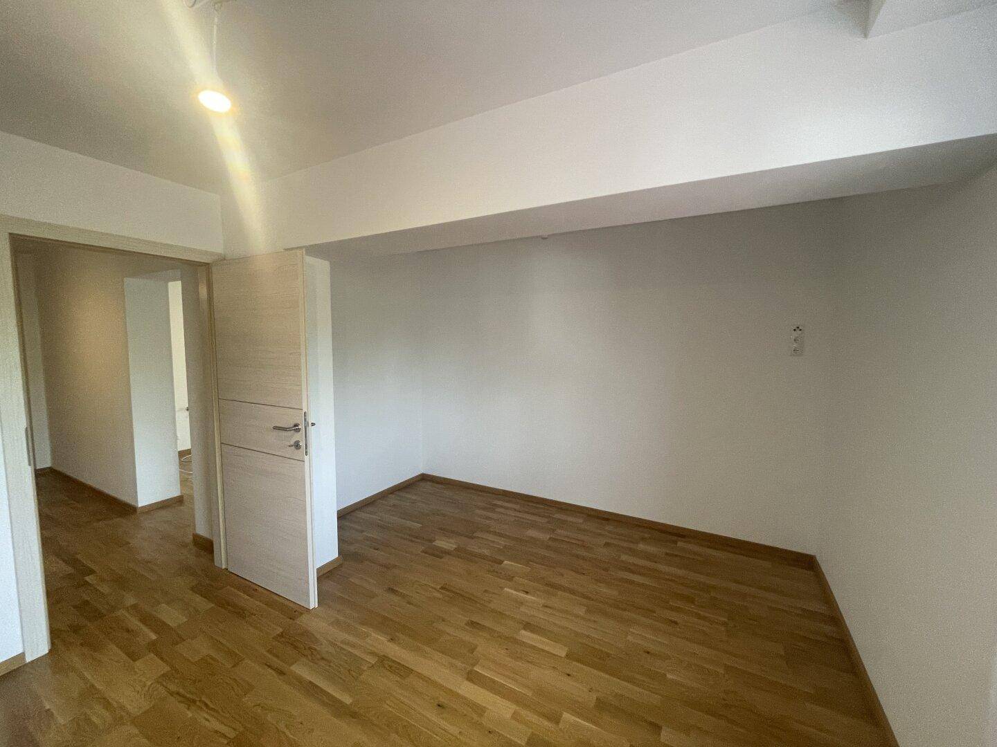 Heller Raum mit Holzparkettboden und weiß gestrichenen Wänden, ideal als Wohn- oder Schlafzimmer.