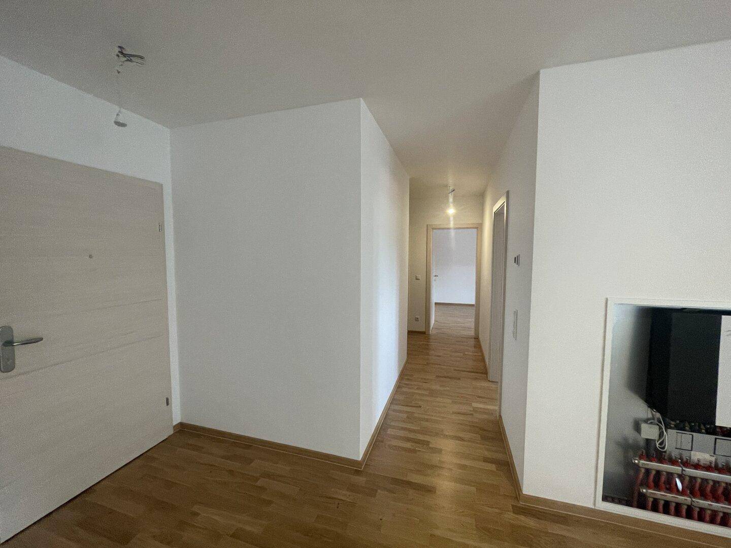 Heller Flur mit Holzparkettboden, der zu verschiedenen Räumen führt.