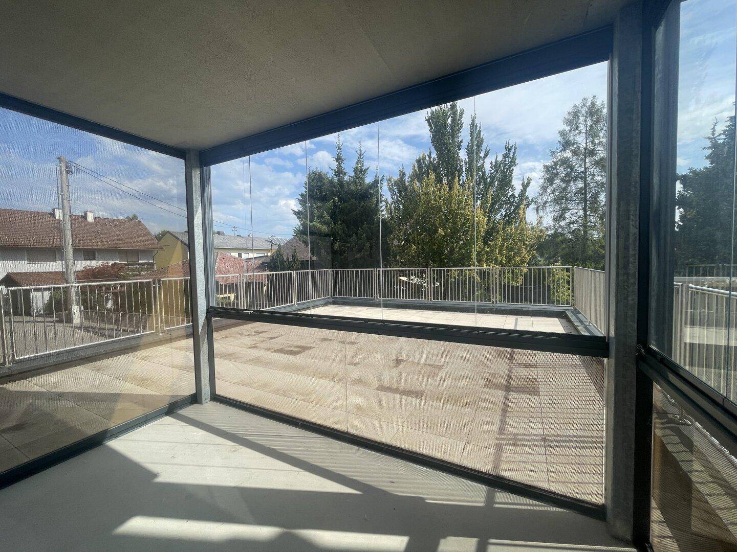 Verglaste Loggia mit Blick auf die Umgebung und angrenzender offener Terrasse.