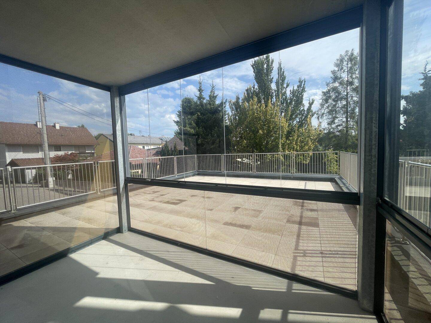Verglaste Loggia mit weitem Blick über die Dächer und angrenzender Terrasse.