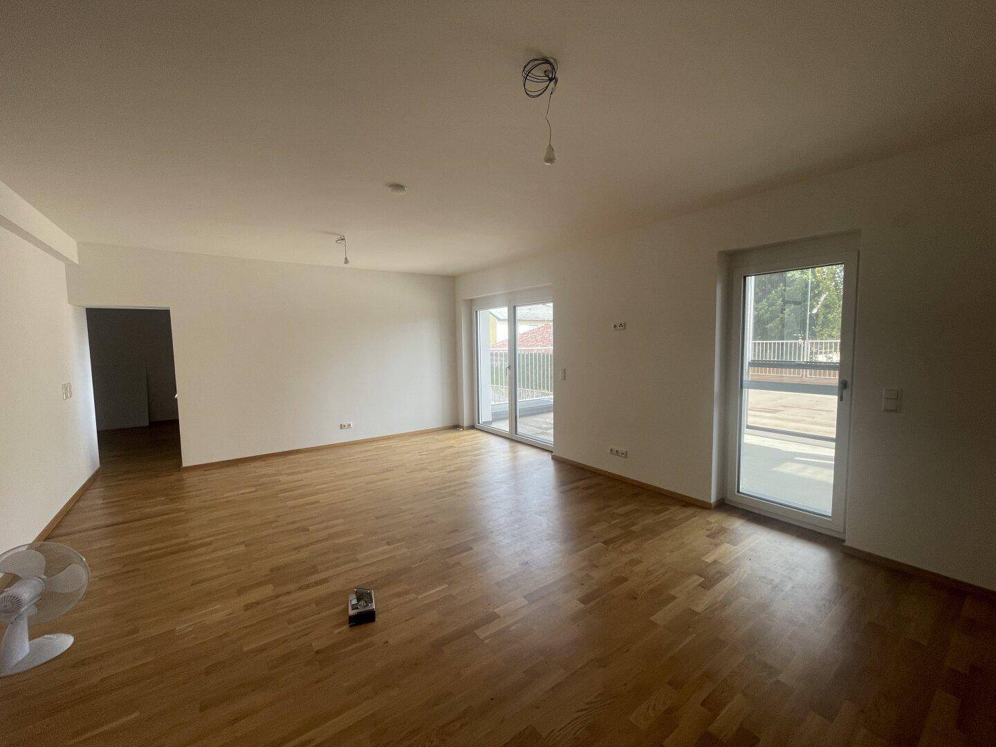 Großer, heller Wohnbereich mit Parkettboden und Zugang zu einer Terrasse.