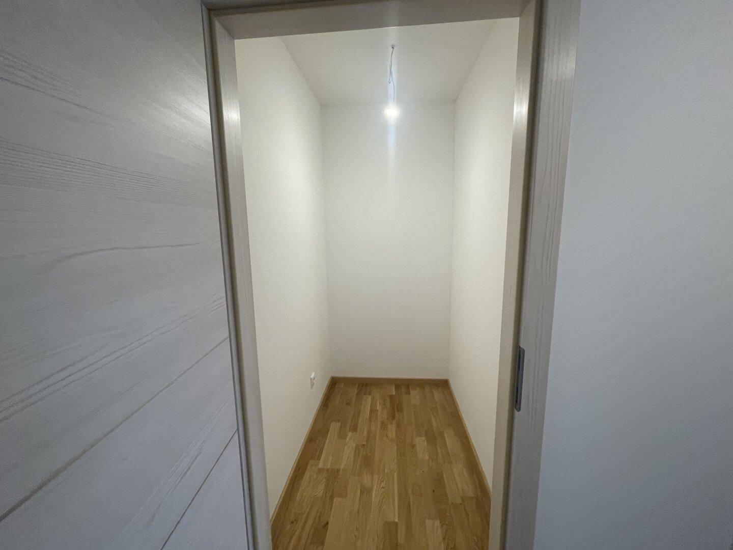 Kleiner, leerer Abstellraum mit hellem Holzfußboden, ideal für zusätzlichen Stauraum.